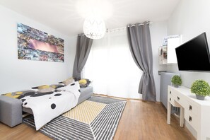 Una camera da letto moderna con un letto, una TV, un termosifone e una finestra con tende.