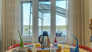 A breakfast table with a coffee pot, teapot, and teacup set, along with a basket of bread and a glass of orange juice. - Apartment with sea view, large terrace, garden, parking, air conditioning in every room (Mali Lošinj)