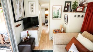 A compact living space with a kitchen area, a television, a sofa, and a dining area. - Your next outdoor oasis (Brinnon)