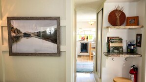 A hallway with a framed landscape painting, a wooden stool, and a fire extinguisher. - Your next outdoor oasis (Brinnon)
