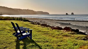 A beach with a row of blue Adirondack chairs facing the ocean. - 4 guest · Eddie Bauer`s former Beachfront Cottage (Sekiu)