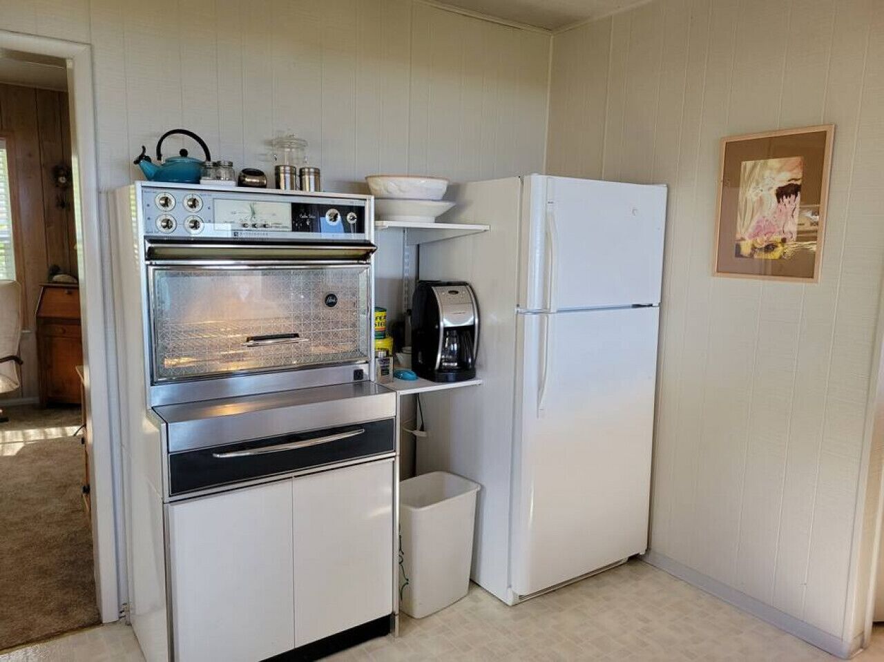A compact kitchen with a built-in oven, a coffee maker, and a refrigerator.