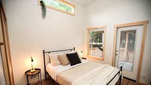 A bedroom with a bed, bedside tables, a window, and a door. - Tiny home in the heart of Forks w/starlink & yard (Forks)