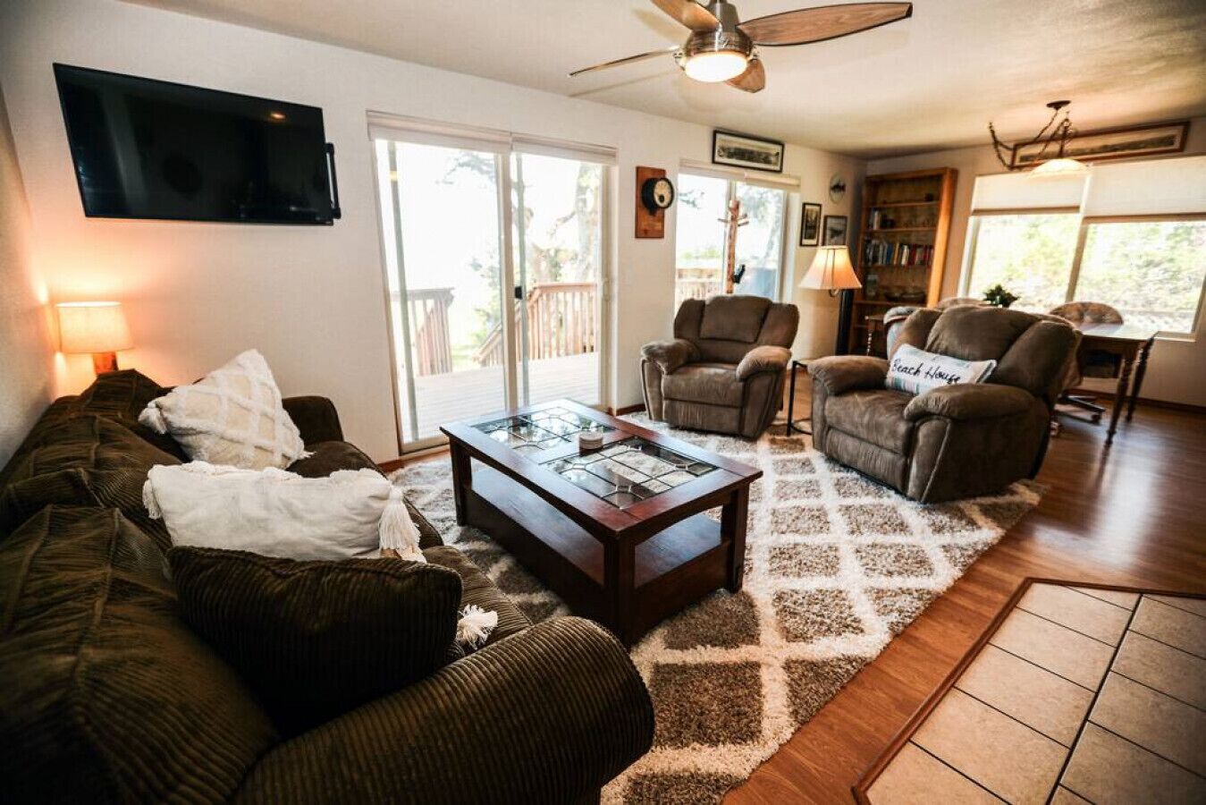 A living room with a sofa, two armchairs, a coffee table, and a TV mounted on the wall.
