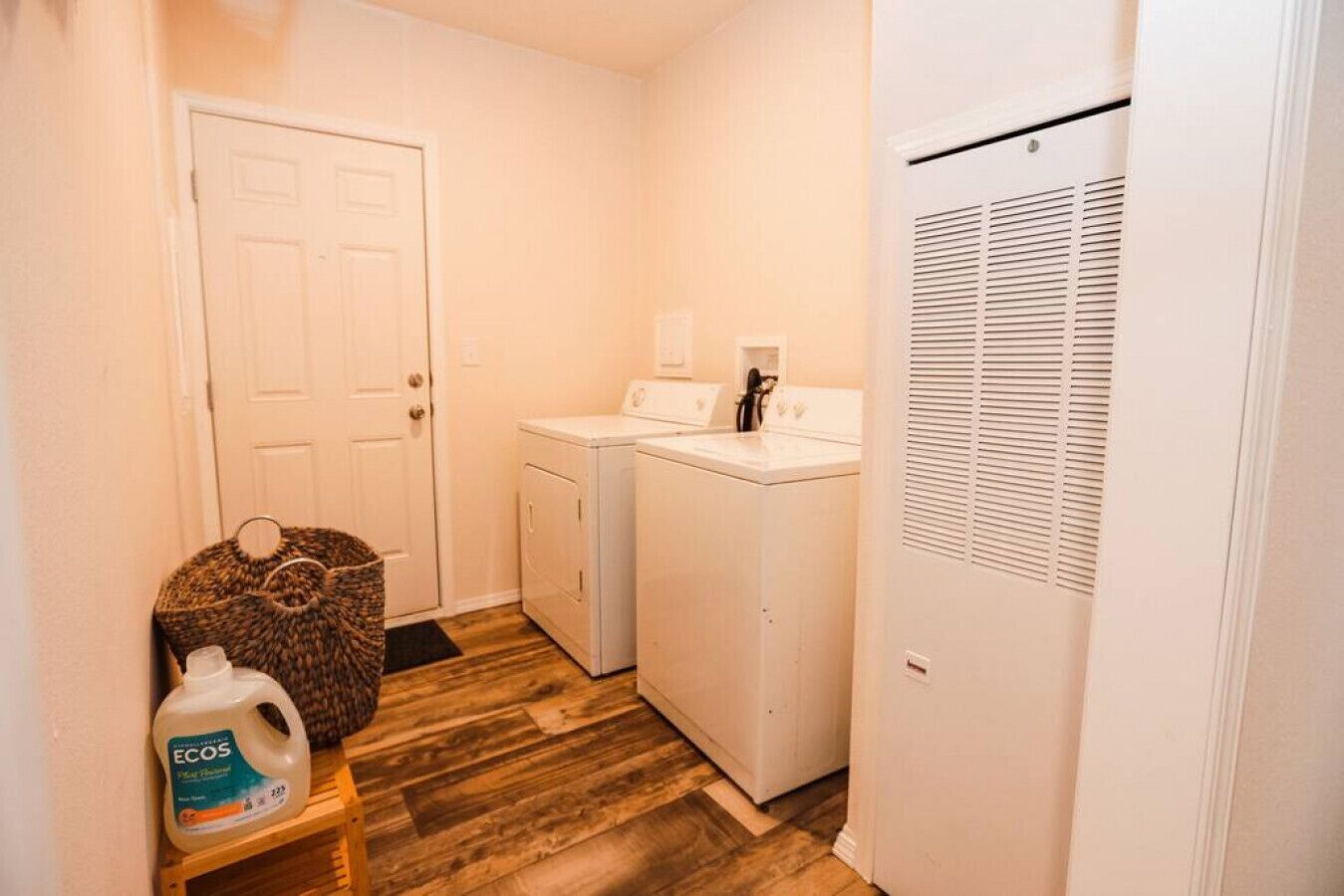 A laundry room with a washing machine, dryer, and a bottle of liquid detergent on a shelf.