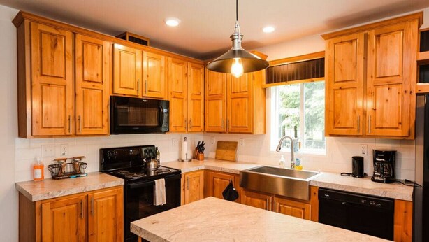 A kitchen with wooden cabinets, a black microwave, a stove, a sink, and a coffee maker. - Your perfect Base Camp: Central, pet friendly w/ Starlink (Forks)
