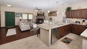 Una cocina moderna con una isla central, una zona de comedor con sofá y sillas, y una chimenea.