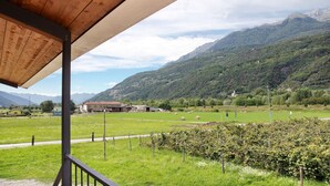 A wooden structure with a view of a green field and mountains in the background. - Studio 'Agriturismo L'isola Del Cavallo 2' with Mountain View, Shared Garden and Wi-Fi (Talamona)
