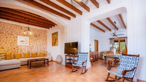 Una sala de estar con sofá, sillones mecedores, televisor y comedor con mesa y sillas.