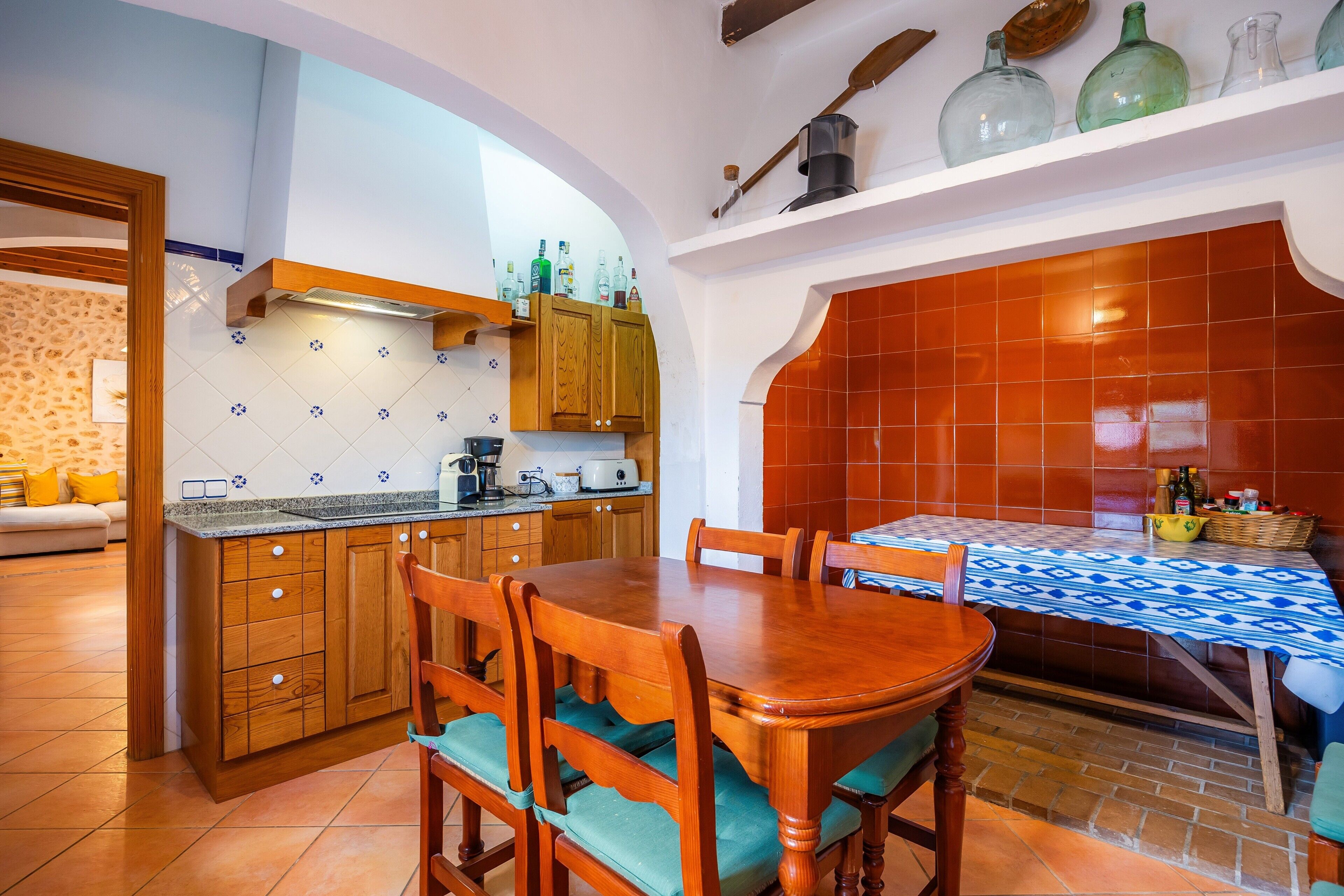 A kitchen with wooden cabinets, a dining table, and a tiled backsplash.