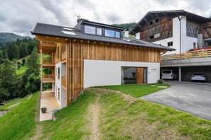 A modern wooden house with a balcony, a garage, and a view of the surrounding landscape.