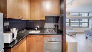 Una cocina moderna con armarios de madera, encimera negra, horno empotrado y ventana con vistas a la ciudad.