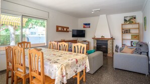 Een woonkamer met een eethoek, open haard, televisie en boekenkasten.