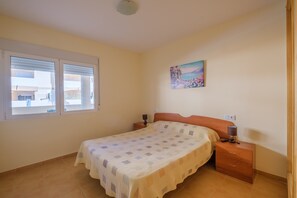 A bedroom with a bed, nightstand, lamp, and a painting on the wall.