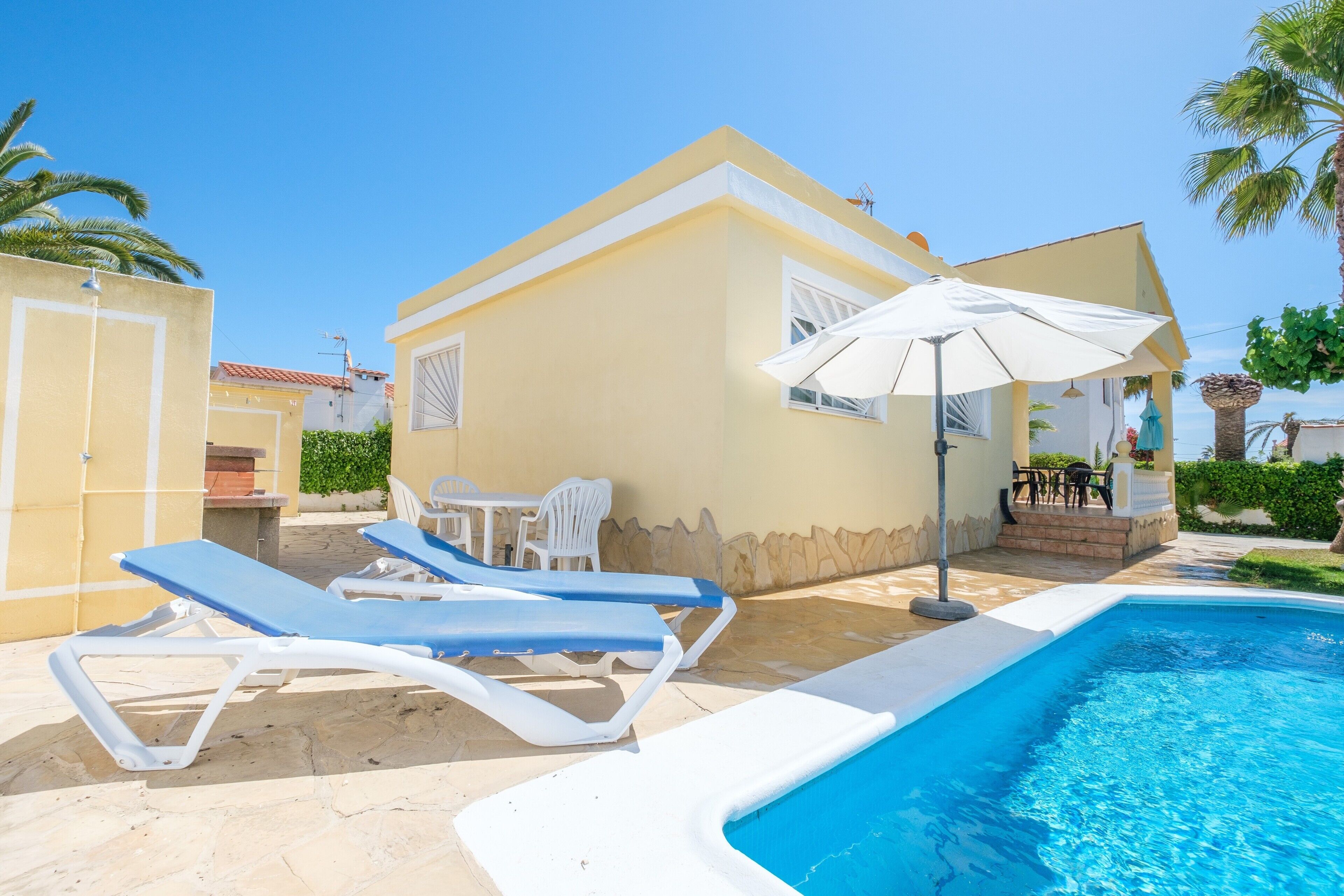 A poolside area with lounge chairs, a table, and an umbrella.