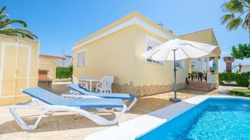 A poolside area with lounge chairs, a table, and an umbrella.