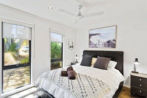 Relax in this serene bedroom with a large bed, ceiling fan, and stunning outdoor views.