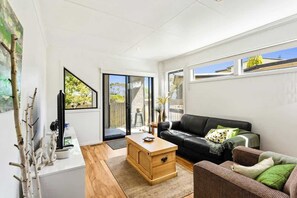 A modern living room with a sofa, a coffee table, and a TV.