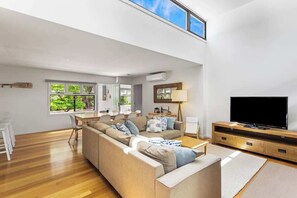 A modern living room with a sofa set, a television, and a dining area with a table and chairs.