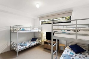 A bunk bed room with a desk and a television. - 5BR Modern Beach House Oasis (Cowes)