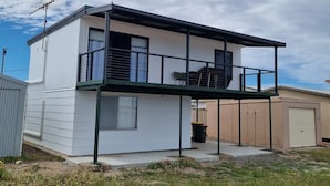 Ein modernes Haus mit zwei Etagen, einem Balkon, einer Garage und einem kleinen Garten.