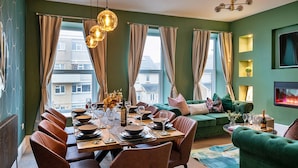 A dining area with a wooden table set for six, surrounded by brown chairs.