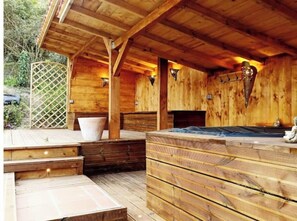 A wooden cabin with a hot tub, wooden deck, and a lattice fence. - Villa Spa: Relaxation in a Green Setting (Limoux)