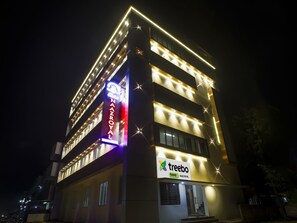 Un hotel de varios pisos con letreros iluminados que dicen 'Naaz Royal' y 'Treebo'.