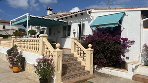 A building with a white exterior, a tiled roof, and a staircase leading to the entrance. - Chic bungalow in a quiet and central location with private pool - close to the beach (Calpe)