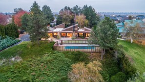 Ein modernes Haus mit Schwimmbad, umgeben von dichtem Grün und Bäumen.
