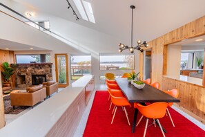 Ein modernes Interieur mit Essbereich, Kamin und großen Fenstern mit Aussicht.