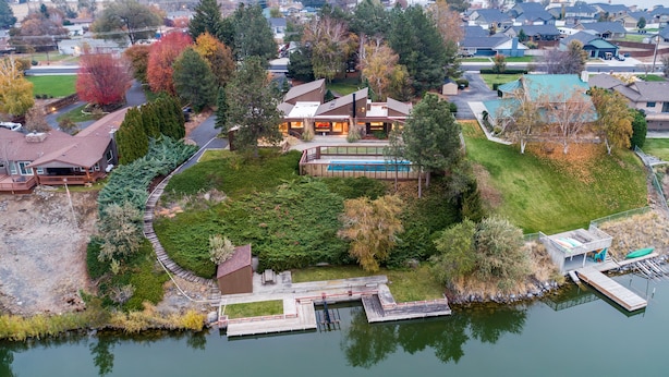 Vue aérienne d’une propriété au bord du lac, avec une grande maison, un quai et une piscine.