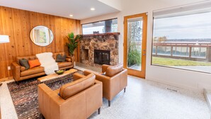 Un salon moderne doté d’une cheminée en pierre, de canapés en cuir et d’une grande fenêtre donnant sur l’extérieur.