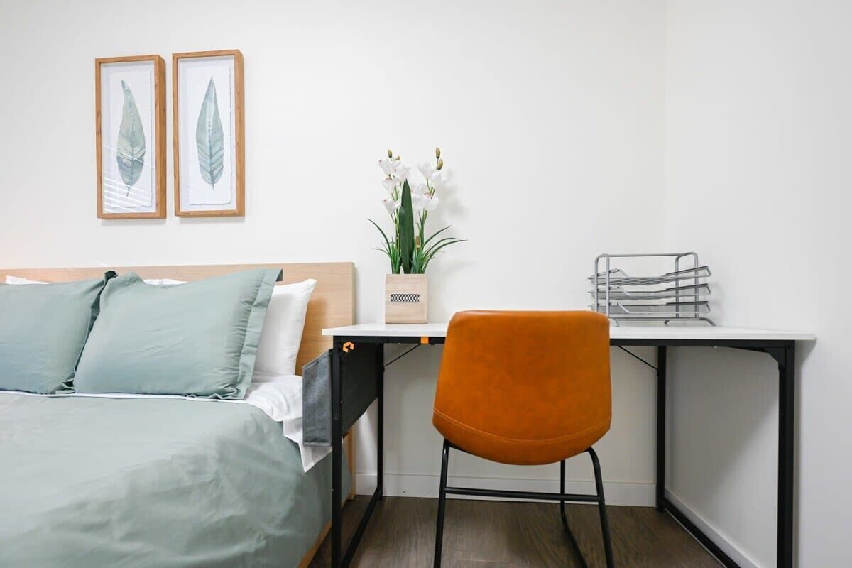 Une chambre à coucher avec un lit, un bureau, une chaise et une plante en pot.