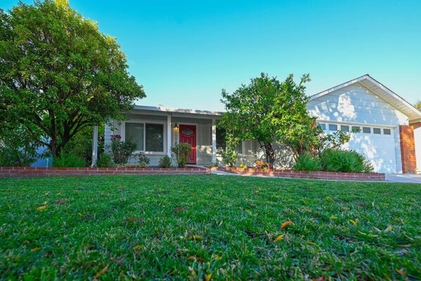 A two-story house with a front lawn, a garage, and a red door. - @ Marbella Lane - Exquisite Home | 3BR (Sunnyvale)