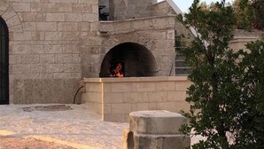 A stone building with a fireplace, a stone bench, and a tree. - Masseria Antoglia (Villa Castelli)