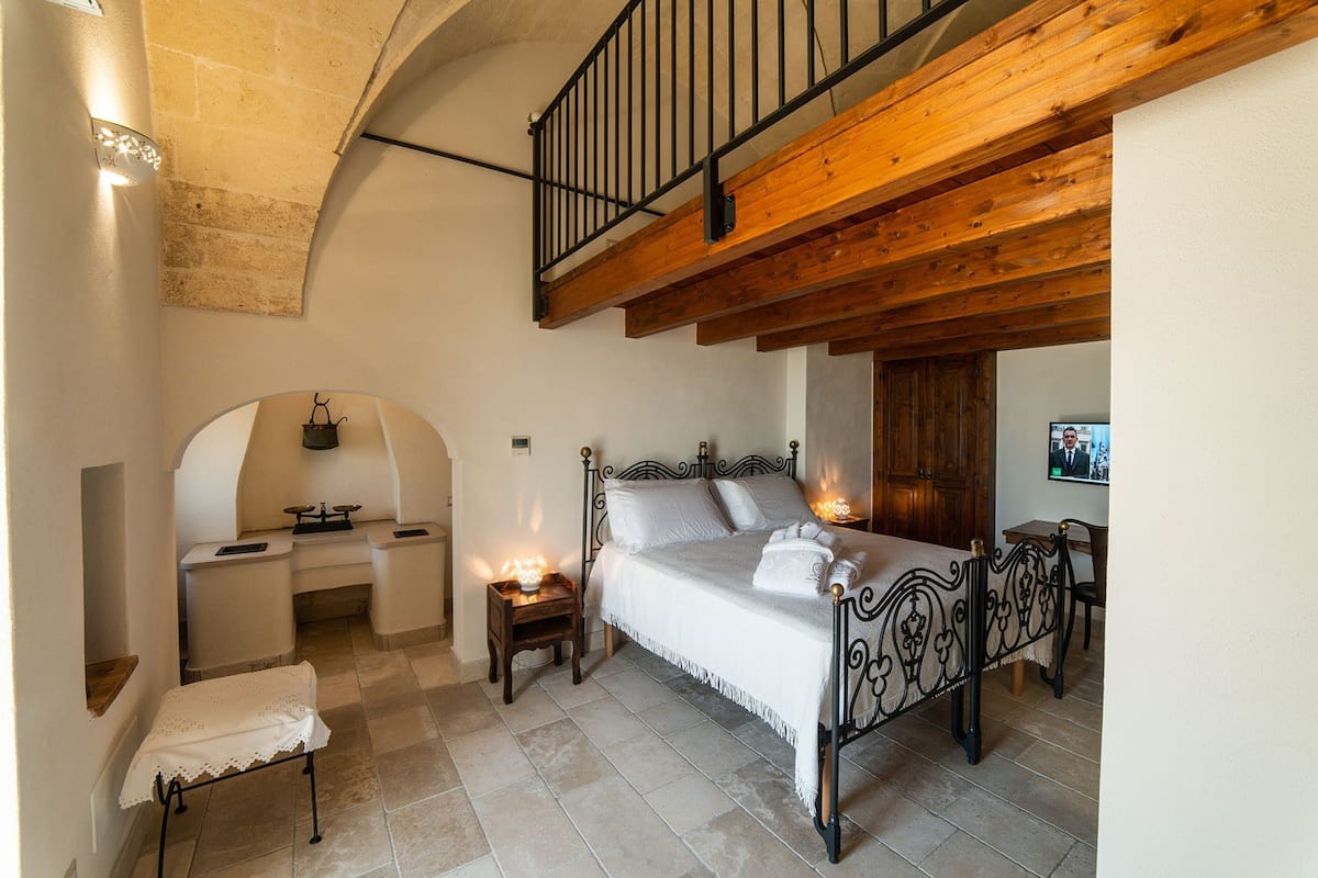 Un dormitorio con cama, mesita de noche y un escritorio pequeño con silla.