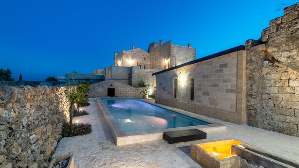 A stone building with a swimming pool, stone walls, and a view of the sea. - Masseria Antoglia (Villa Castelli)