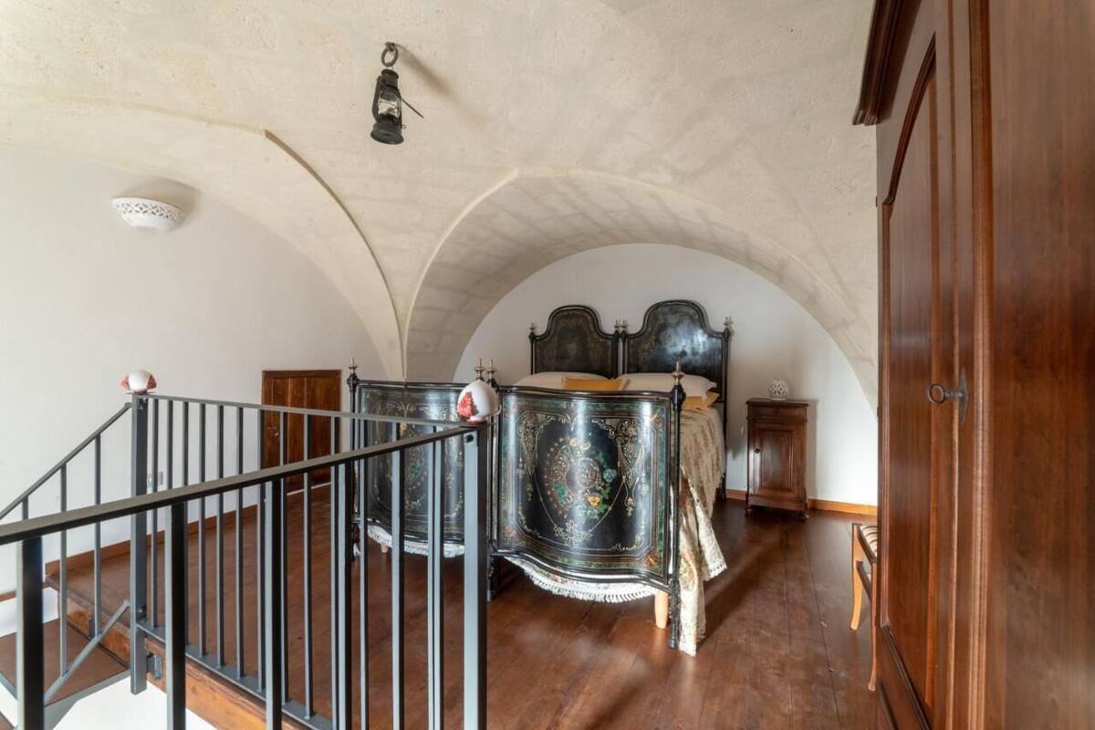 Un dormitorio con una cama de madera, un armario de madera y una escalera con barandilla de metal.