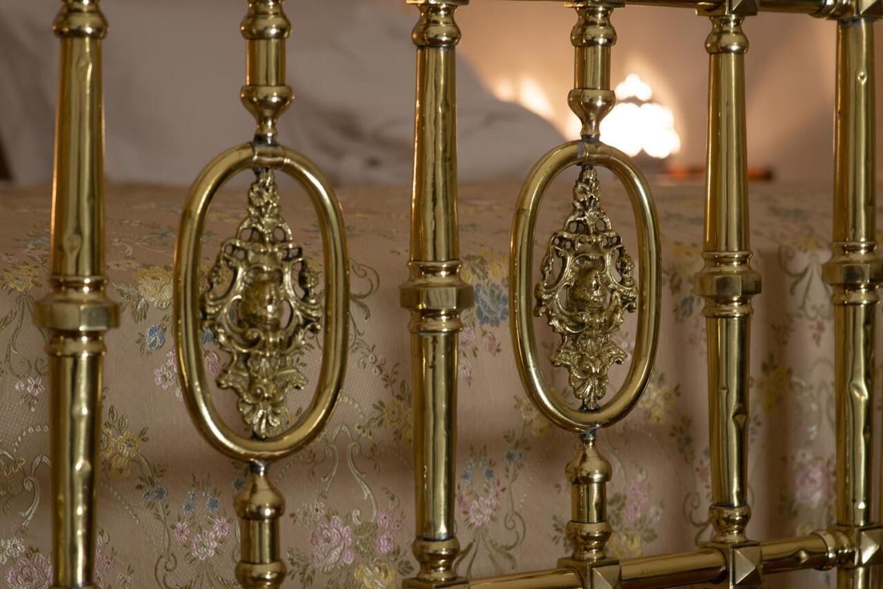 A bed with ornate brass headboard and floral-patterned bedding.