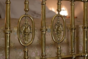 A bed with ornate brass headboard and floral-patterned bedding. - Masseria Antoglia  (Villa Castelli)