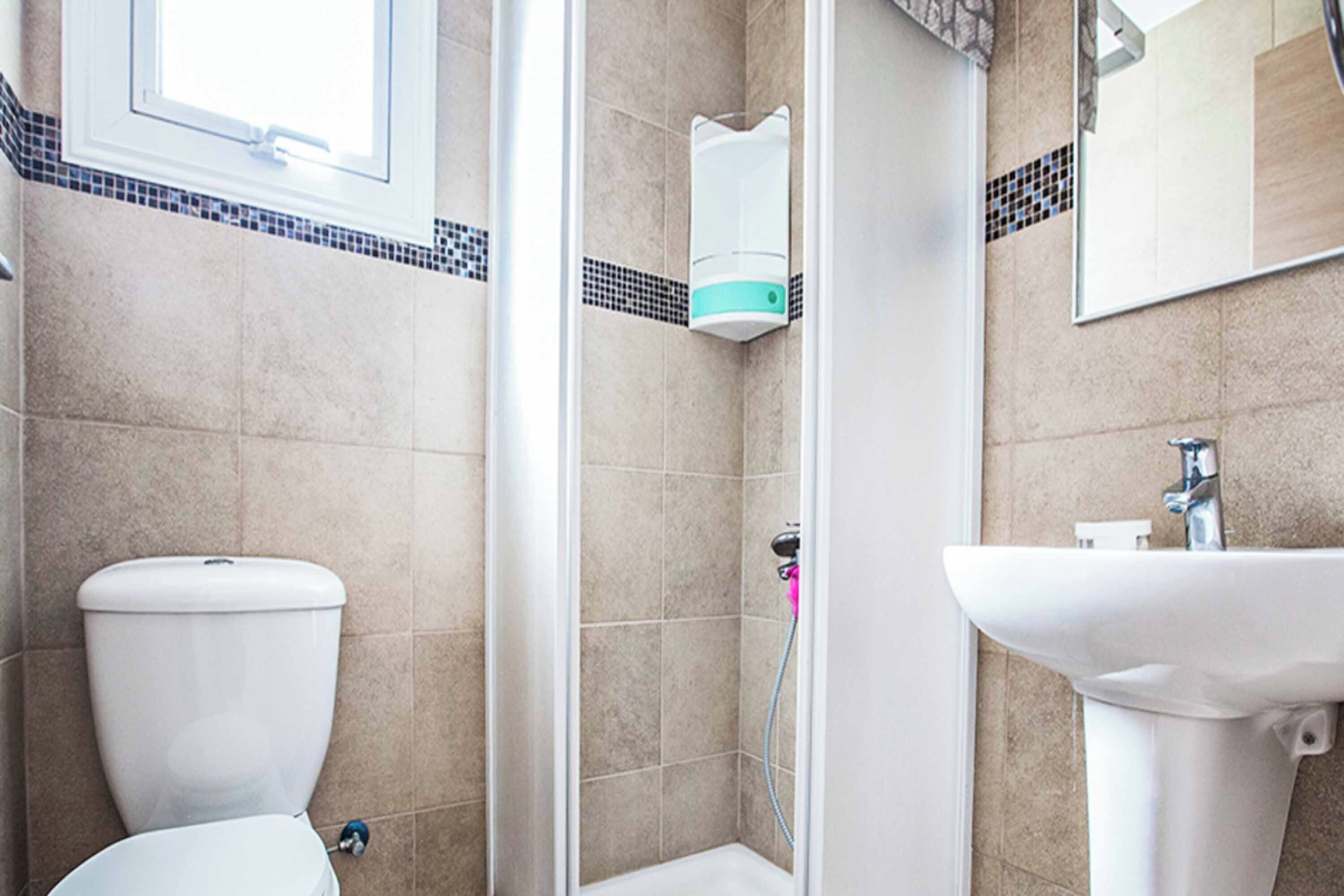 A bathroom with a toilet, a shower, and a sink.