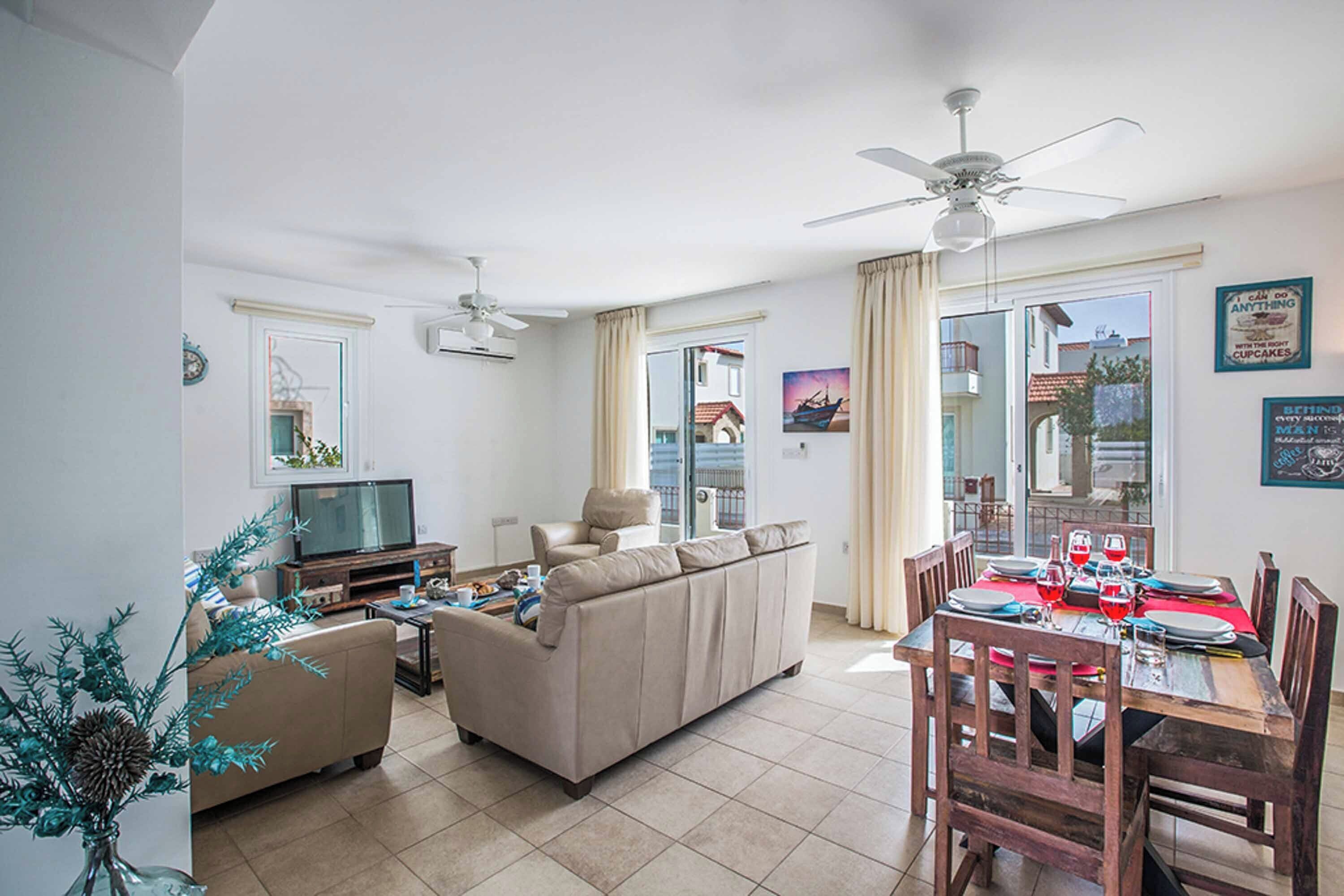 A living room with a sofa, TV, and dining table set for six.