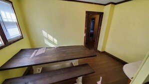 A room with a dark wooden table and bench, yellow walls, and a visible door leading to another room. - Spacious ATV Retreat House (Rock)