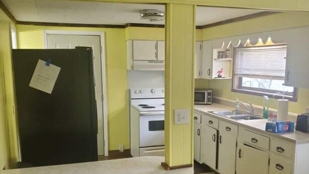 A kitchen with yellow walls, a refrigerator, an oven, a sink, and cabinets. - Spacious ATV Retreat House (Rock)