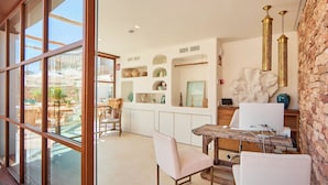 A modern kitchen with a wooden table, chairs, and a large window overlooking a garden. - Mar Suites Formentera by Universal Beach Hotels (Formentera)