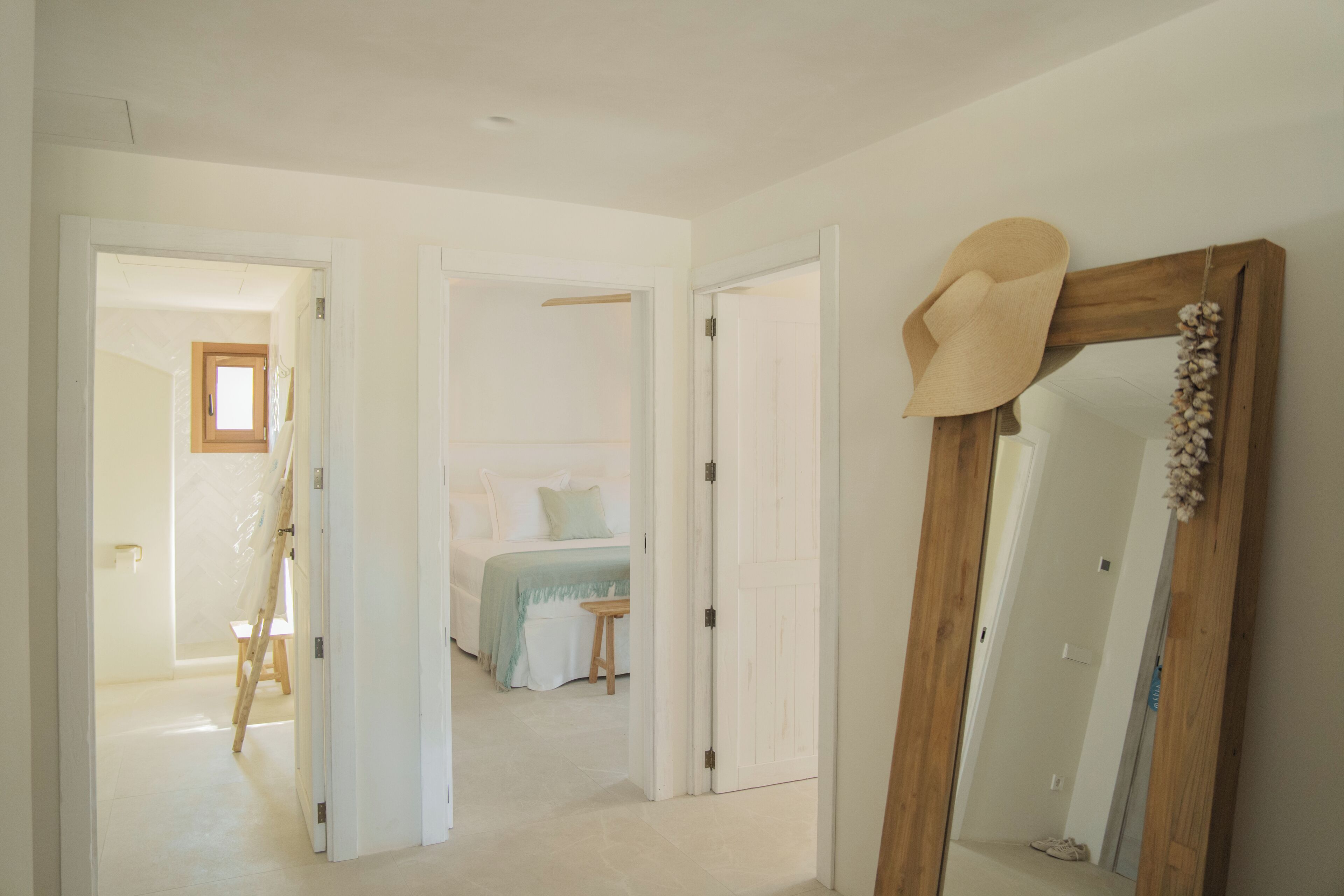 Ein Zimmer mit einem Bett, einer Holztür und einem Spiegel, auf dem ein Hut liegt.