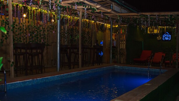 A pool area with a wooden deck, lounge chairs, and a neon sign. - Go2Hotel45 (Lagos)