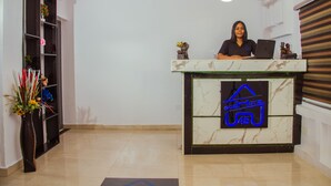 A reception desk with a digital sign displaying the hotel name and logo. - Go2Hotel45 (Lagos)