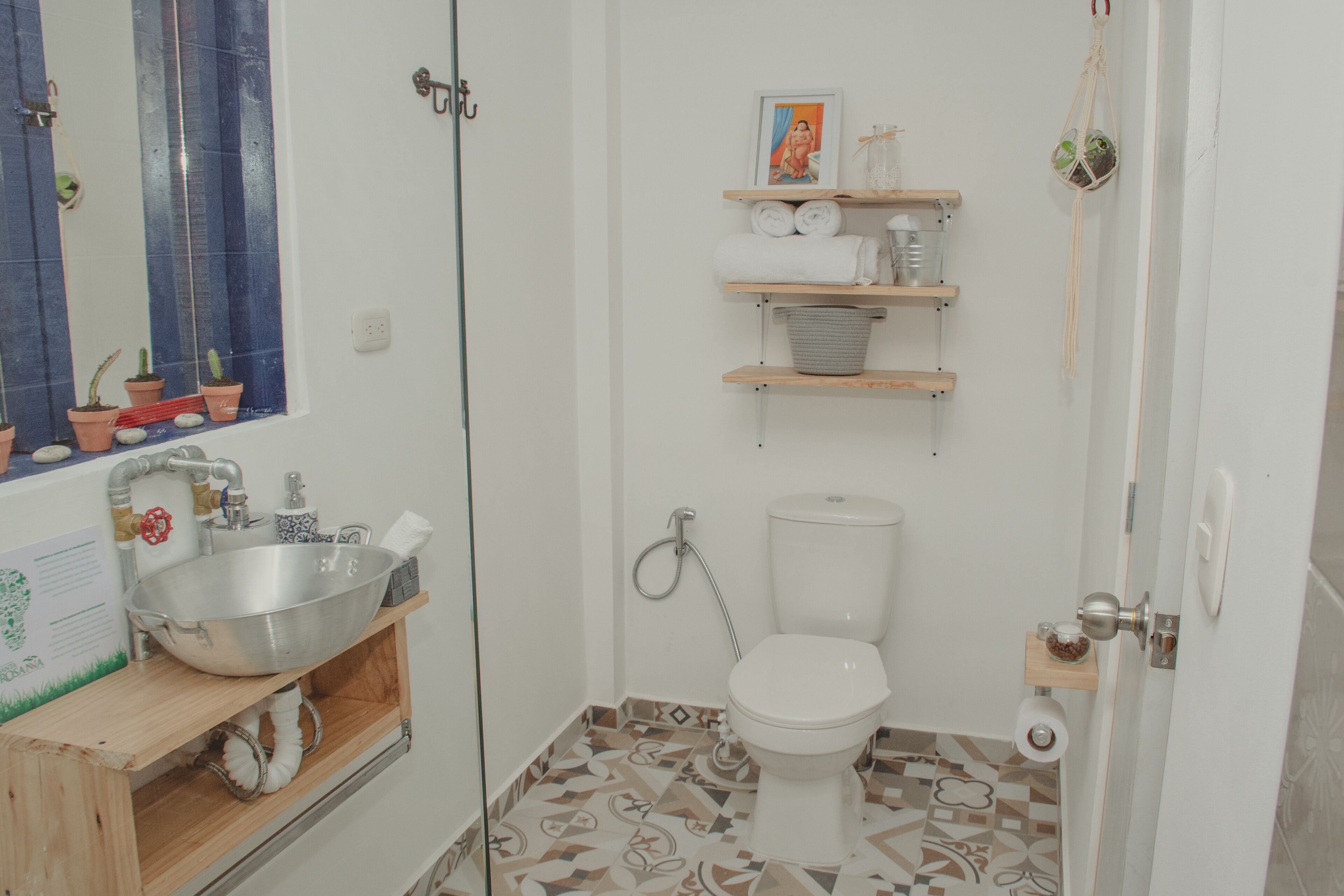 Une petite salle de bain avec un lavabo, des toilettes et des étagères au-dessus des toilettes.